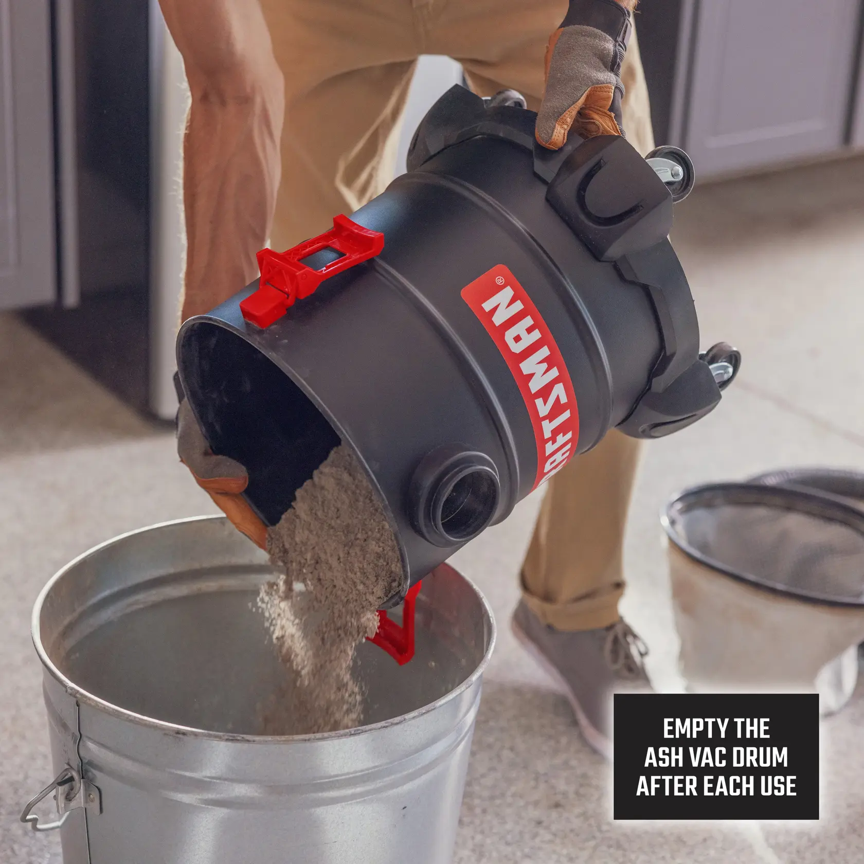 Person empties ash from a CRAFTSMAN vacuum drum into a metal bin. Reminder sign to empty drum after use.