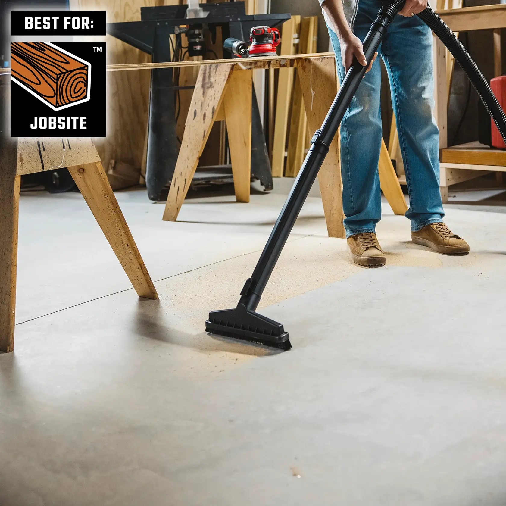 Person cleaning sawdust from jobsite floor with a floor brush and extension wand on wet/dry vac