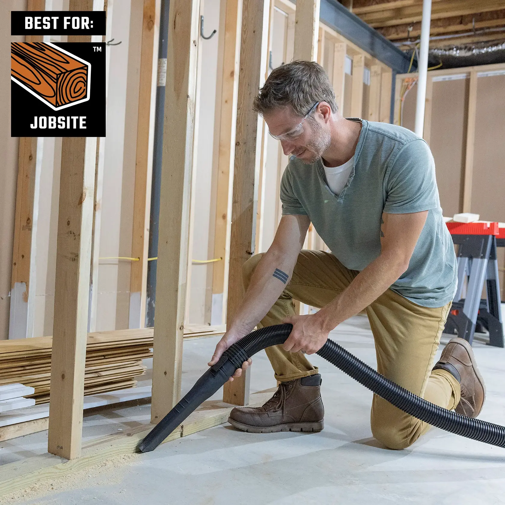 Contractor cleaning up sawdust by newly constructed walls in basement of home with CRAFTSMAN vac