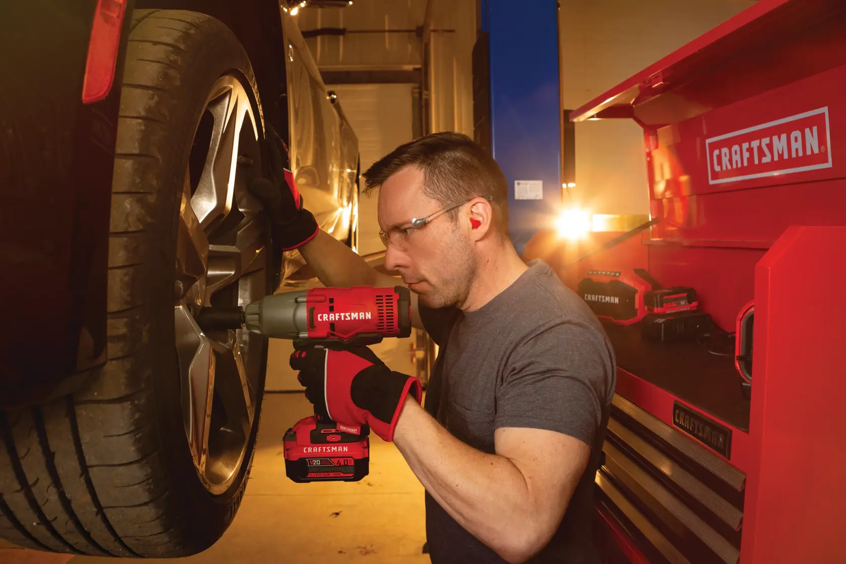 Cordless half inch impact wrench kit 1 battery being used to tighten tyre screws by person.