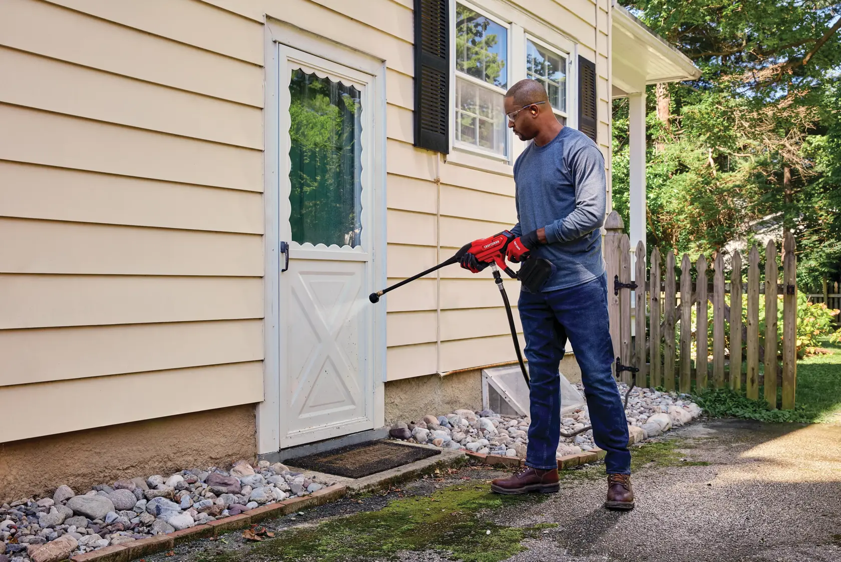 20 volt cordless 350 max P S I power cleaner being used by a person to clean a door outdoors.