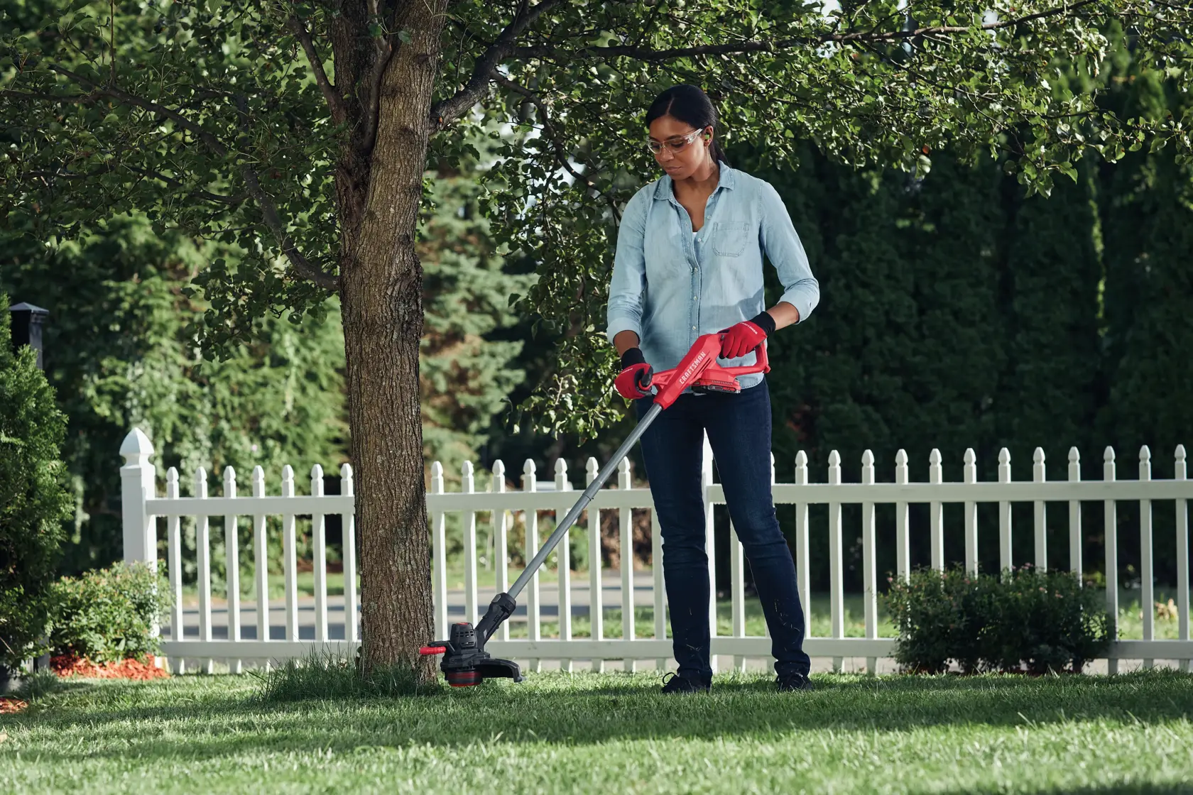 CRAFTSMAN String Trimmer trimming around tree fence in background