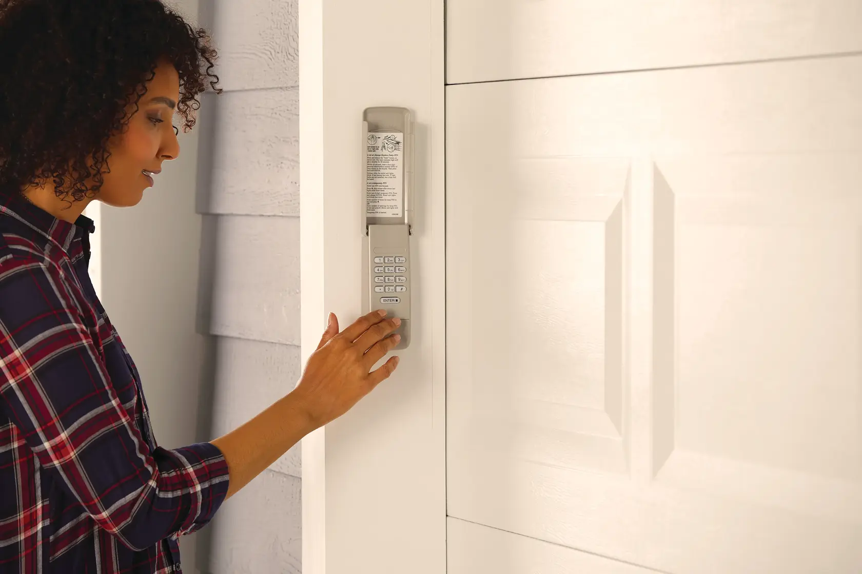 Wireless keypad with all weather cover being used by a person to enter pin.
