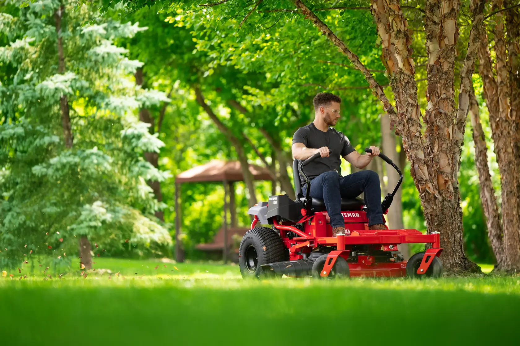Man riding CRAFTSMAN Z3200 Gas Zero-Turn around tree