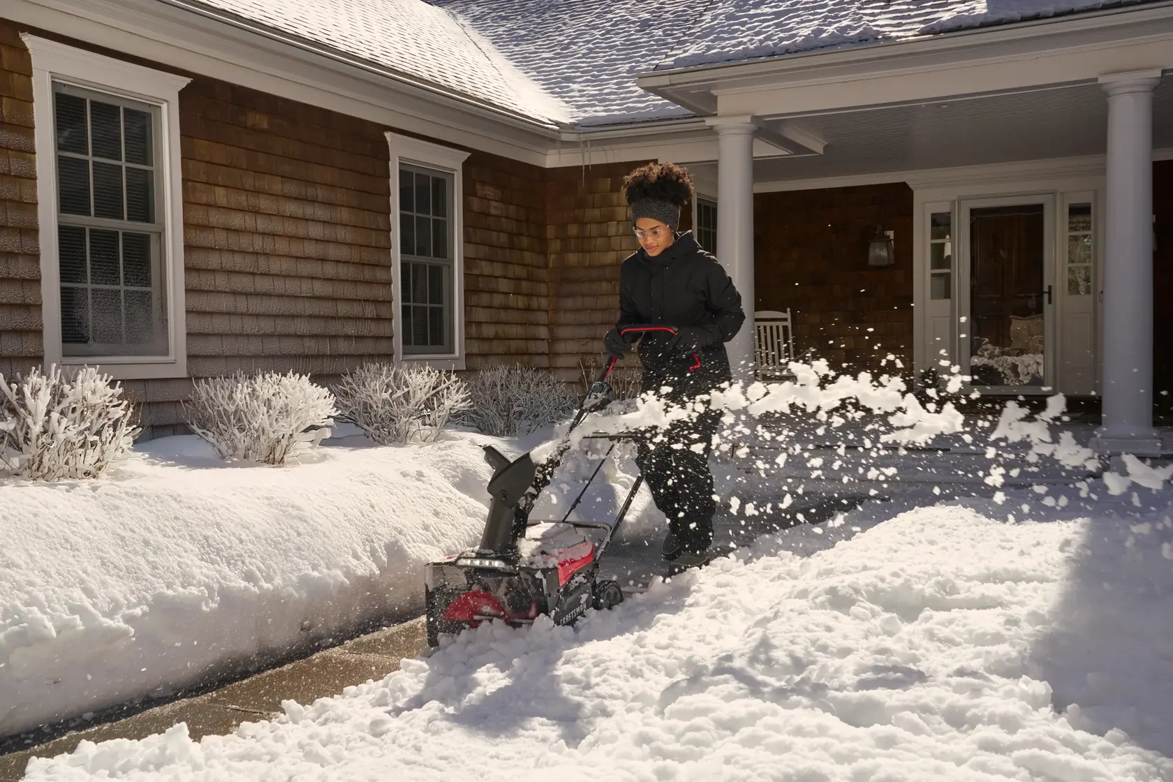 Photo of a person using a Craftsman snow blower, SKU CM32AB2B1CB93, clearing snow on a house walkway.