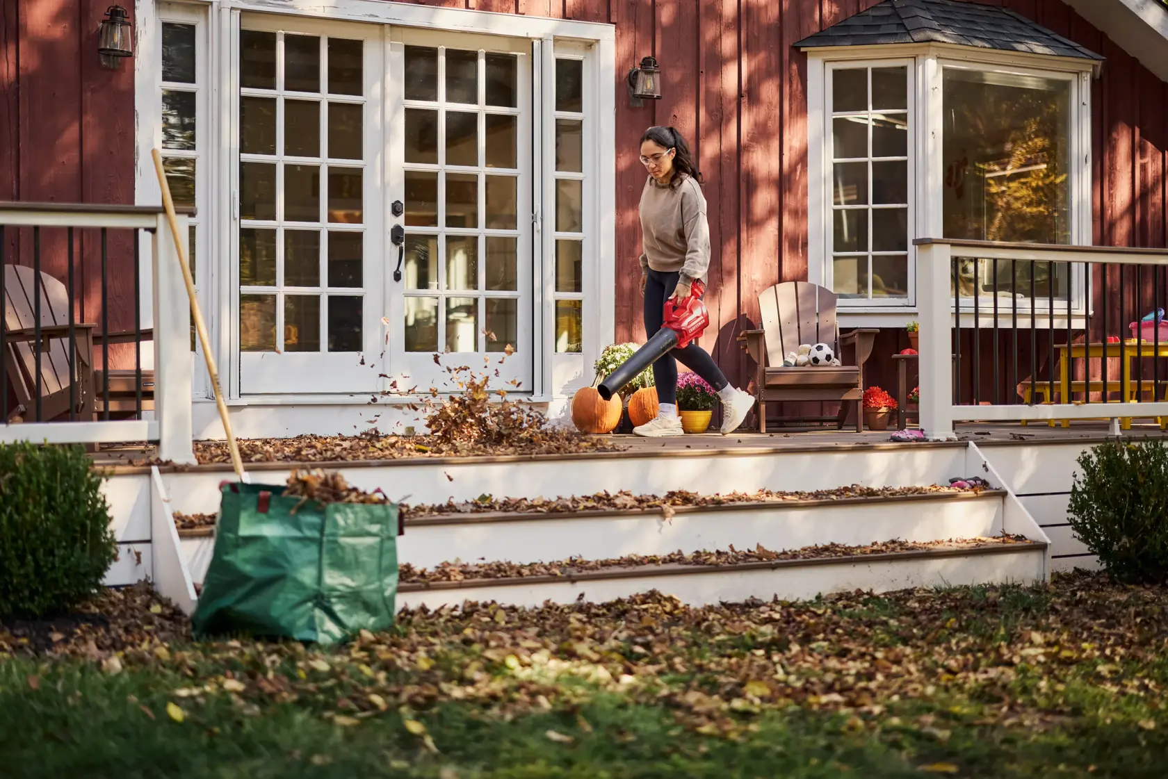 Woman blowing leaves off porch with the CRAFTSMAN� V20* Cordless Axial Leaf Blower