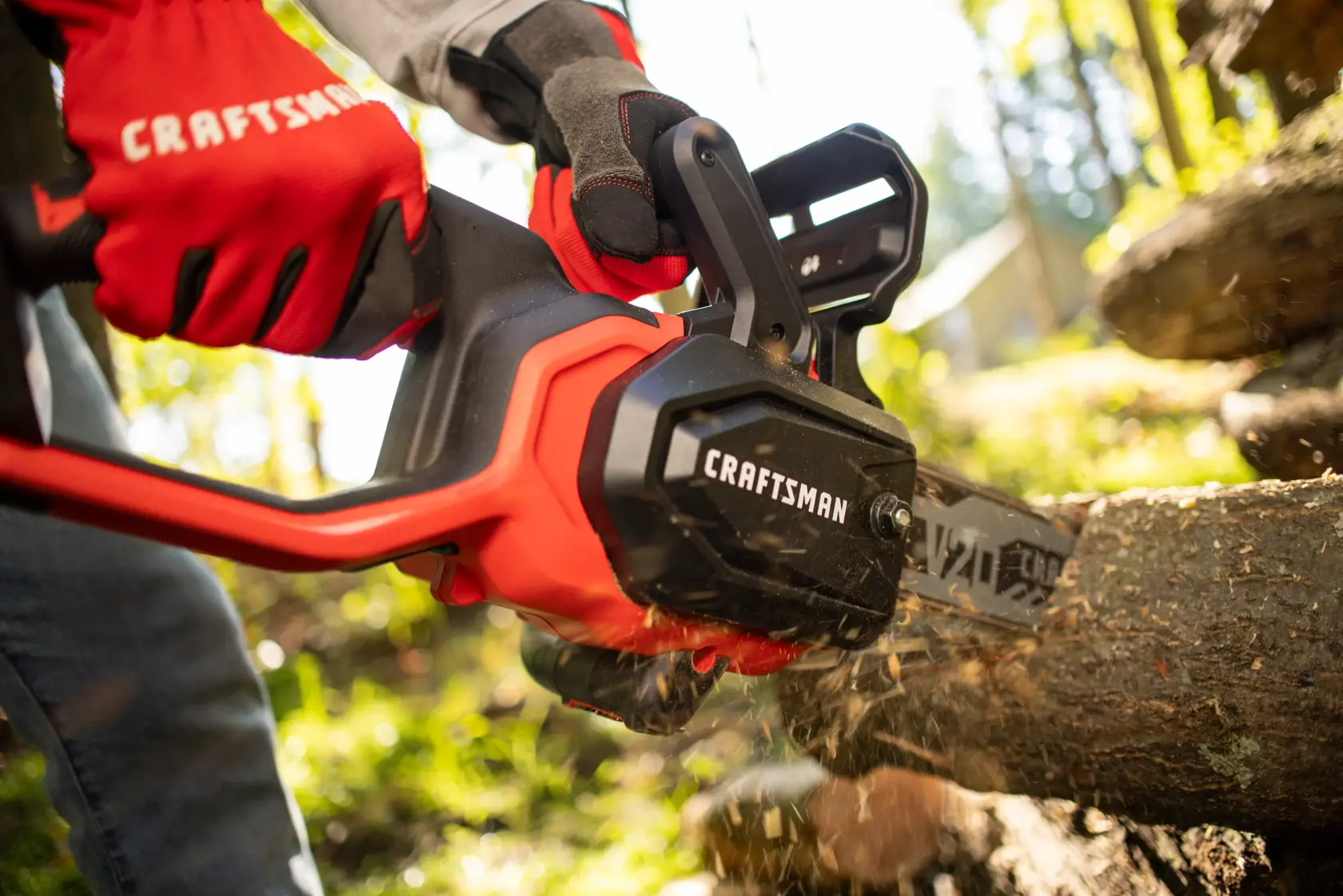 Photo of Craftsman CMCCS630P1 chainsaw cutting wood outdoors, operator wearing red Craftsman gloves.