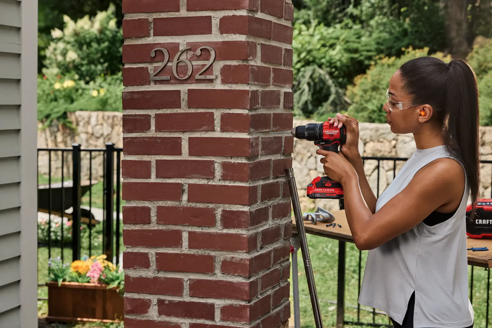 Wide angle of woman drilling into brick with the CRAFTSMAN® V20* BRUSHLESS RP™ Compact Hammer Drill/Driver. Battery and Charger Sold Separately
