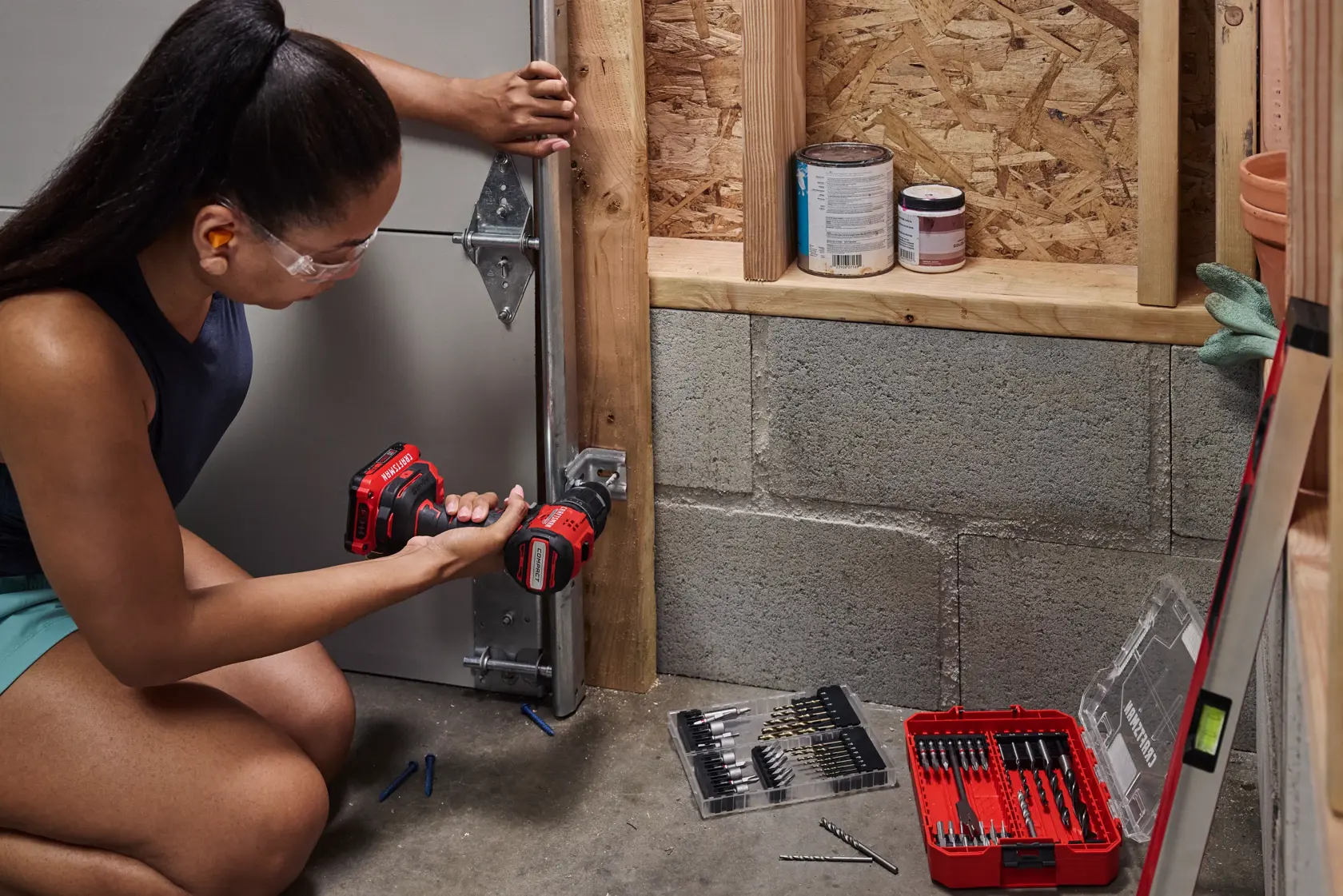 Woman pre drilling a hole for garage door brackets with the CRAFTSMAN® V20* BRUSHLESS RP™ Compact Hammer Drill/Driver.Battery and Charger Sold Separately 