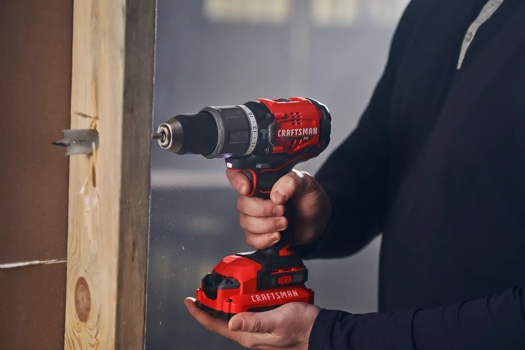 Man in dark shirt drills into wood with CRAFTSMAN V20 drill.