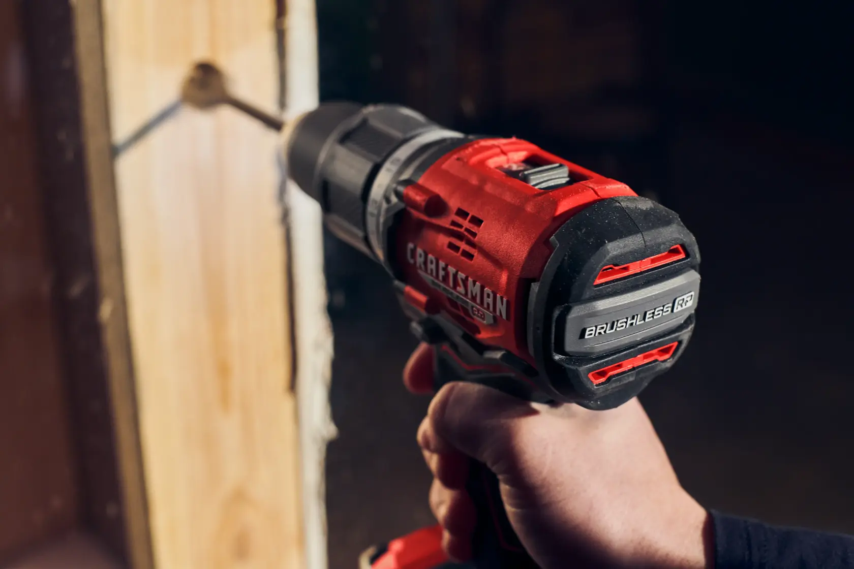 Man in dark shirt drills into wood with CRAFTSMAN V20 drill.