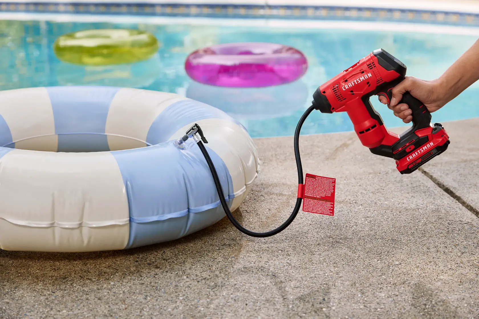 Photo of Craftsman CMCE521B inflator inflating a blue and white pool float by a swimming pool.