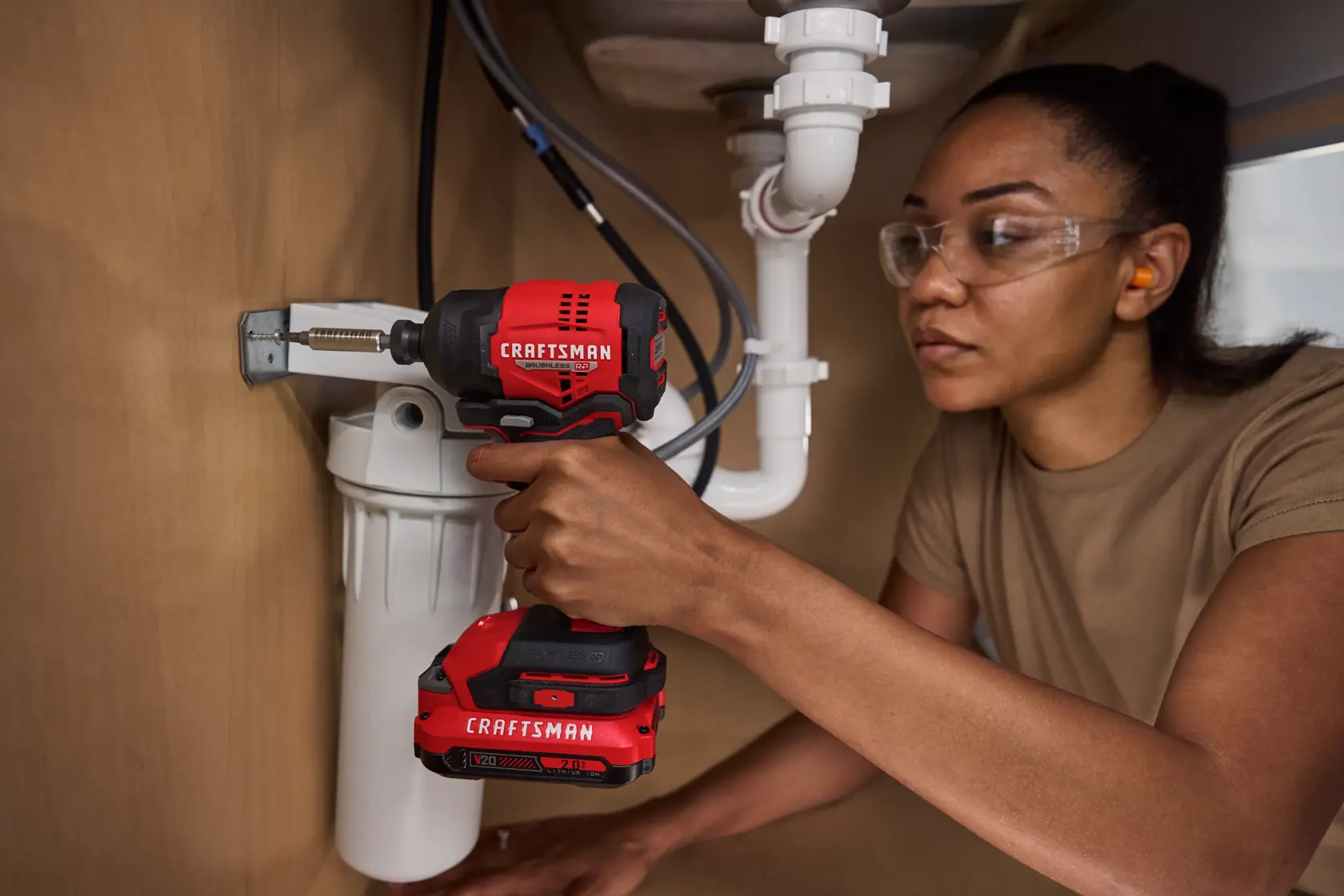Close up woman in tight space under sink driving with the CRAFTSMAN® V20* BRUSHLESS RP™ Compact Impact Driver