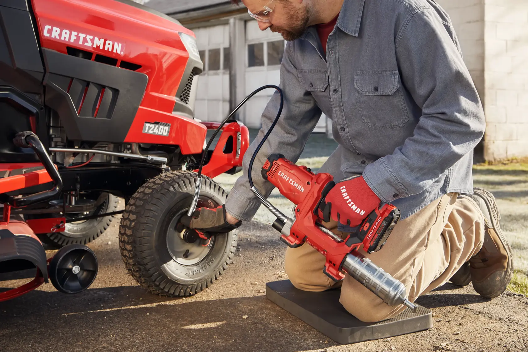 Photo of end-user applying grease with grease gun to farm equipment.