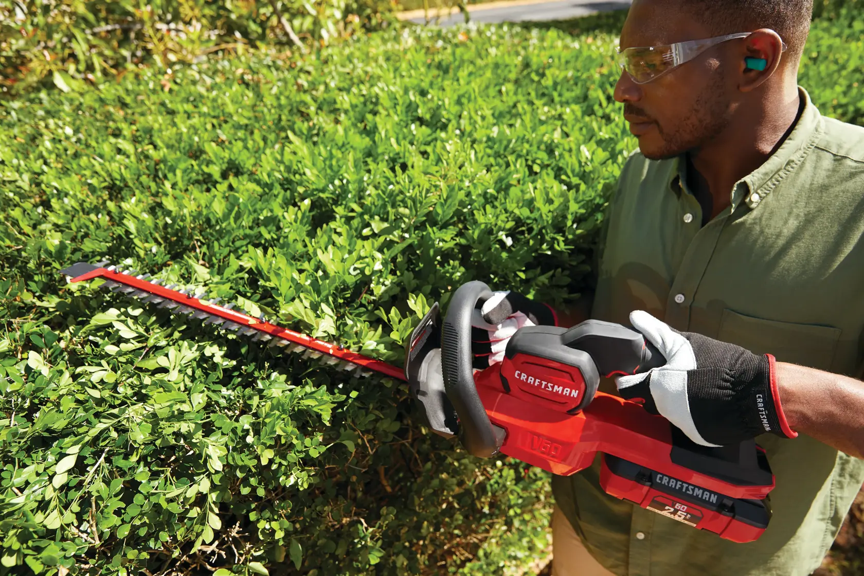 Cordless 24 inch hedge trimmer kit 2.5 Ampere hours being used to trim hedge top.
