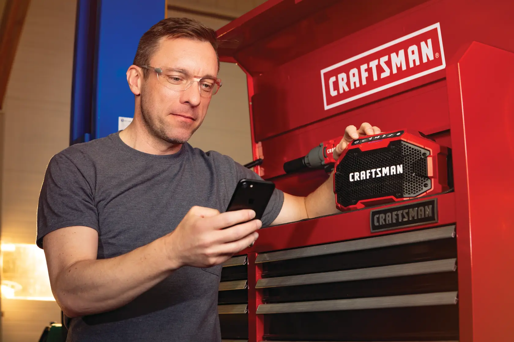 20 volt cordless bluetooth speaker being used by a person to connect a smart phone to stream music.