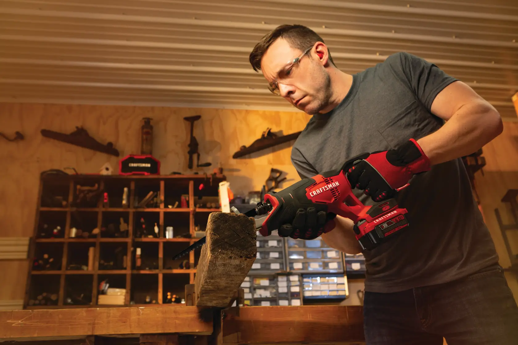 20 volt cordless reciprocating saw kit being used by a person to cut a wooden bar indoors.