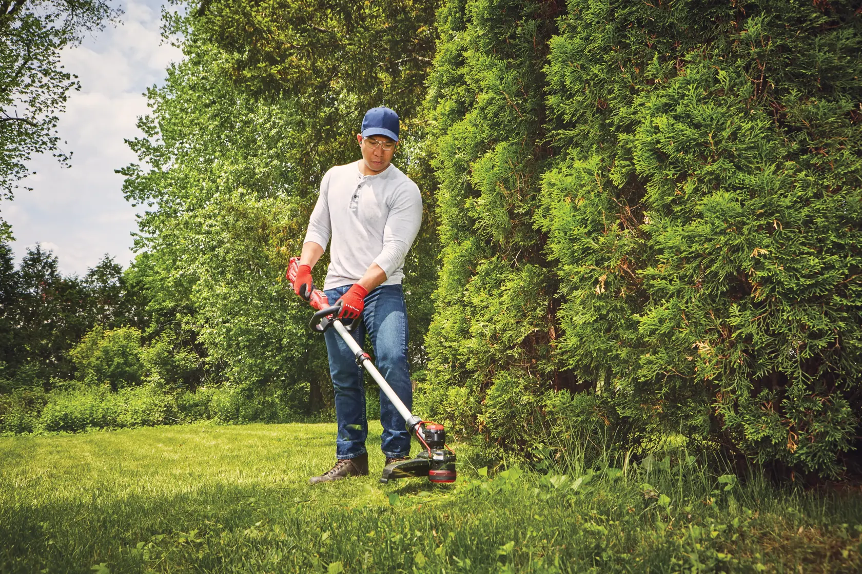 20 volt weedwacker 13 inch cordless string trimmer and edger with push button feed kit being used by a person to cut outgrown weeds.