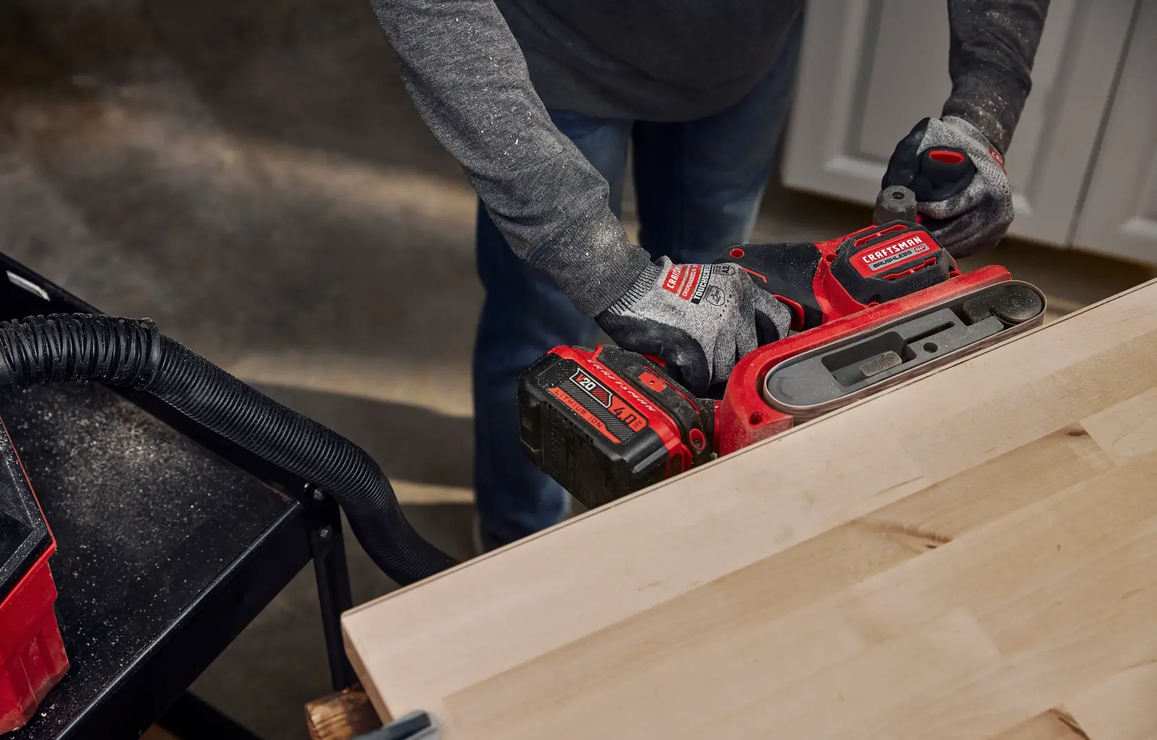 Man operating a Craftsman Brushless RP Belt Sander on the side of butcher block  