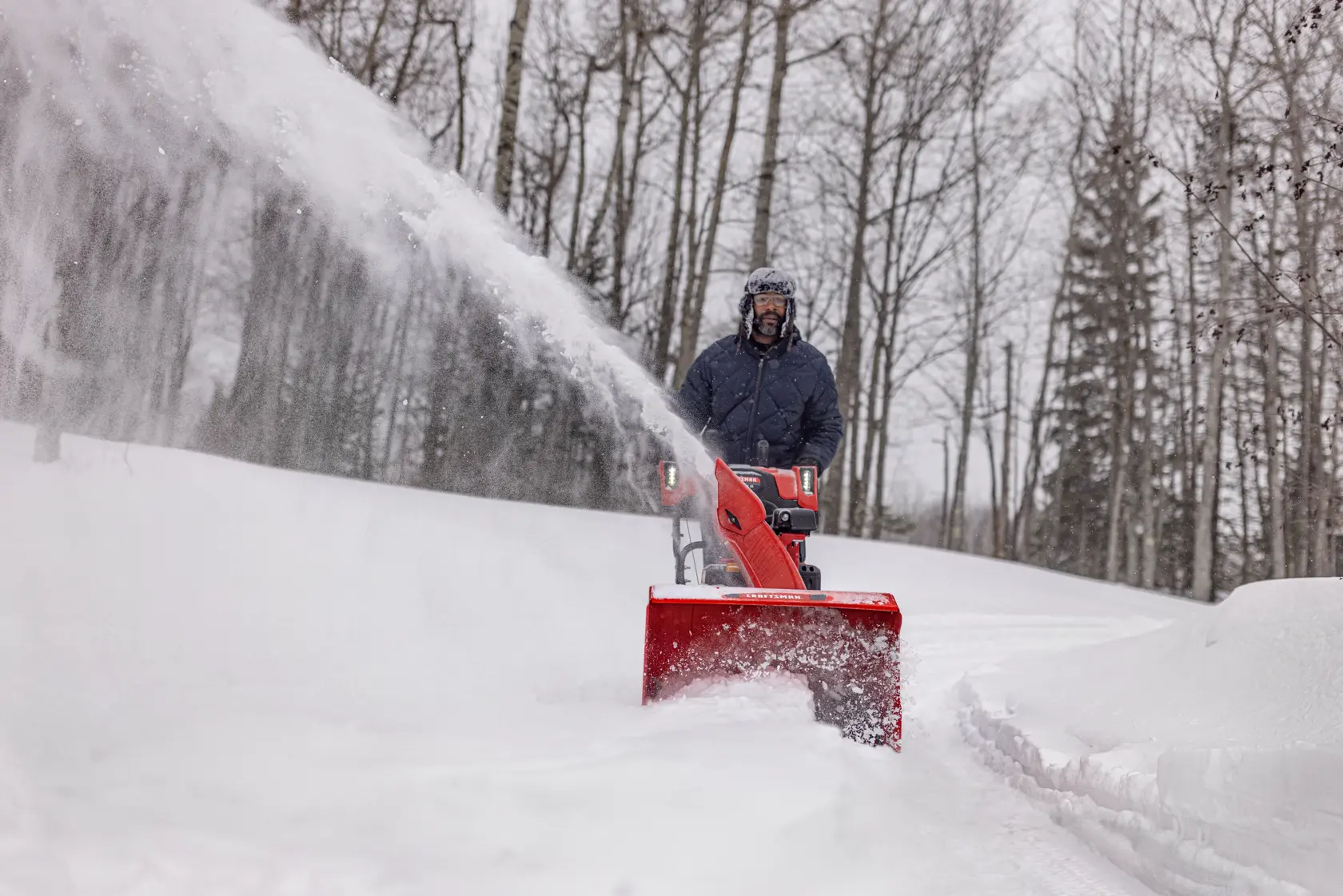 CRAFTSMAN Performance 26 Track Snowblower clearing snow off driveway trees in background