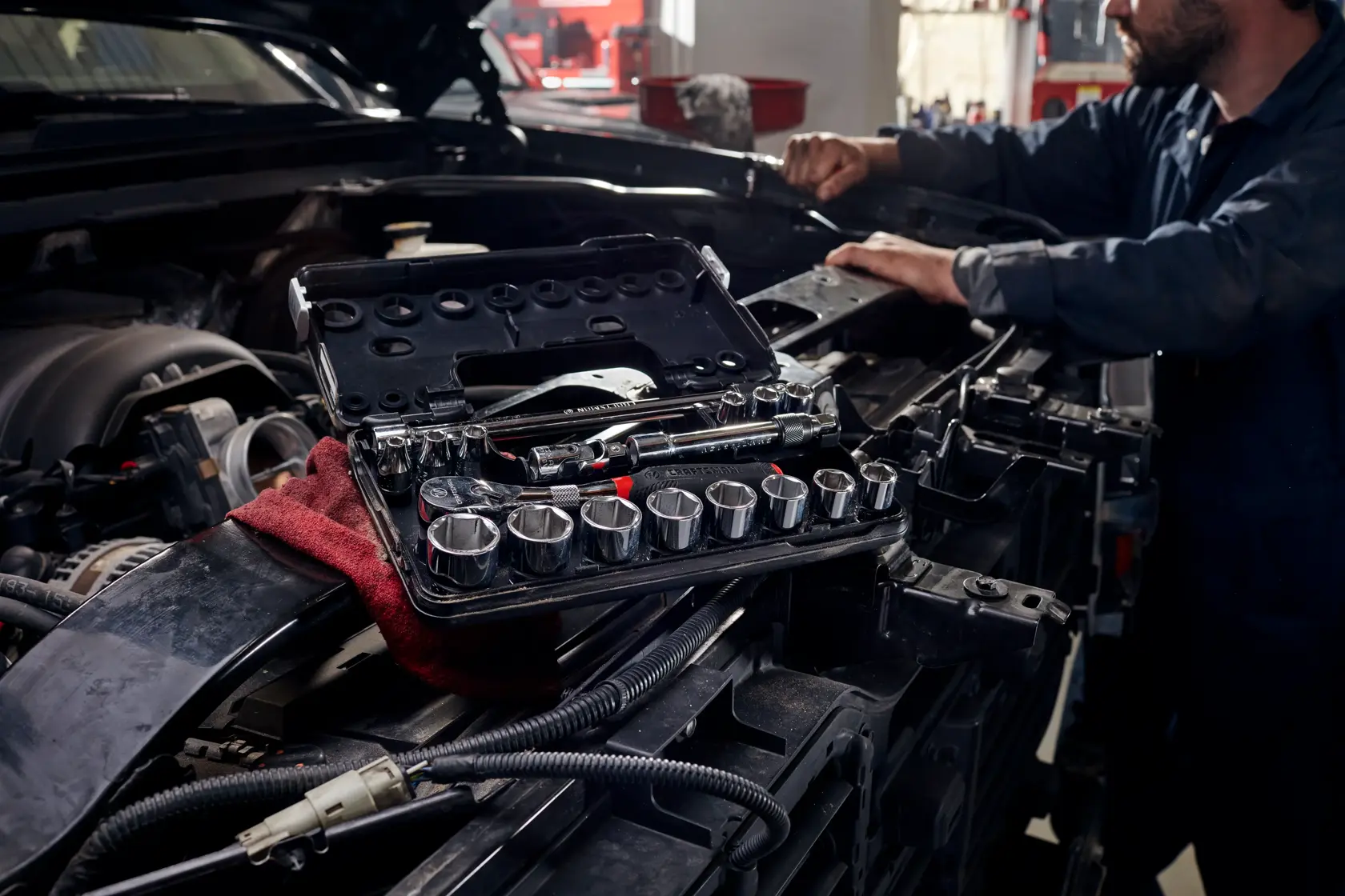 18 piece 3 eight inch drive S A E 6 point tool set being used by a person to fix a car.