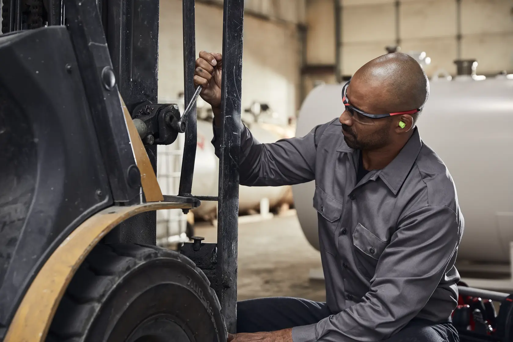Photo of worker using CRAFTSMAN wrench SKU CMMT87350V to repair machinery in an industrial setting.