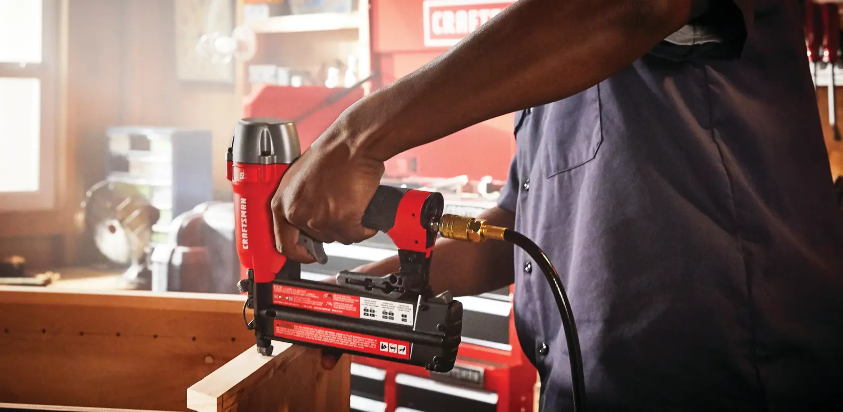 18 gauge brad nailer being used to nail a wooden strip by a person.