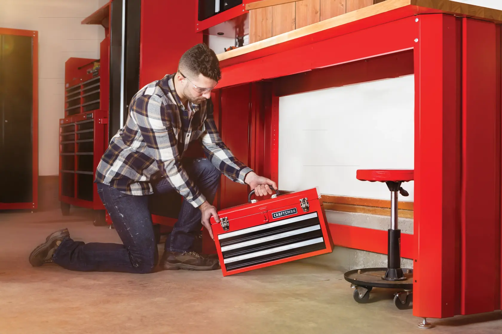 Portable 20 and 5 tenths inch Ball bearing 3 Drawer Red Steel Lockable Tool Box being stored by person under workstation.