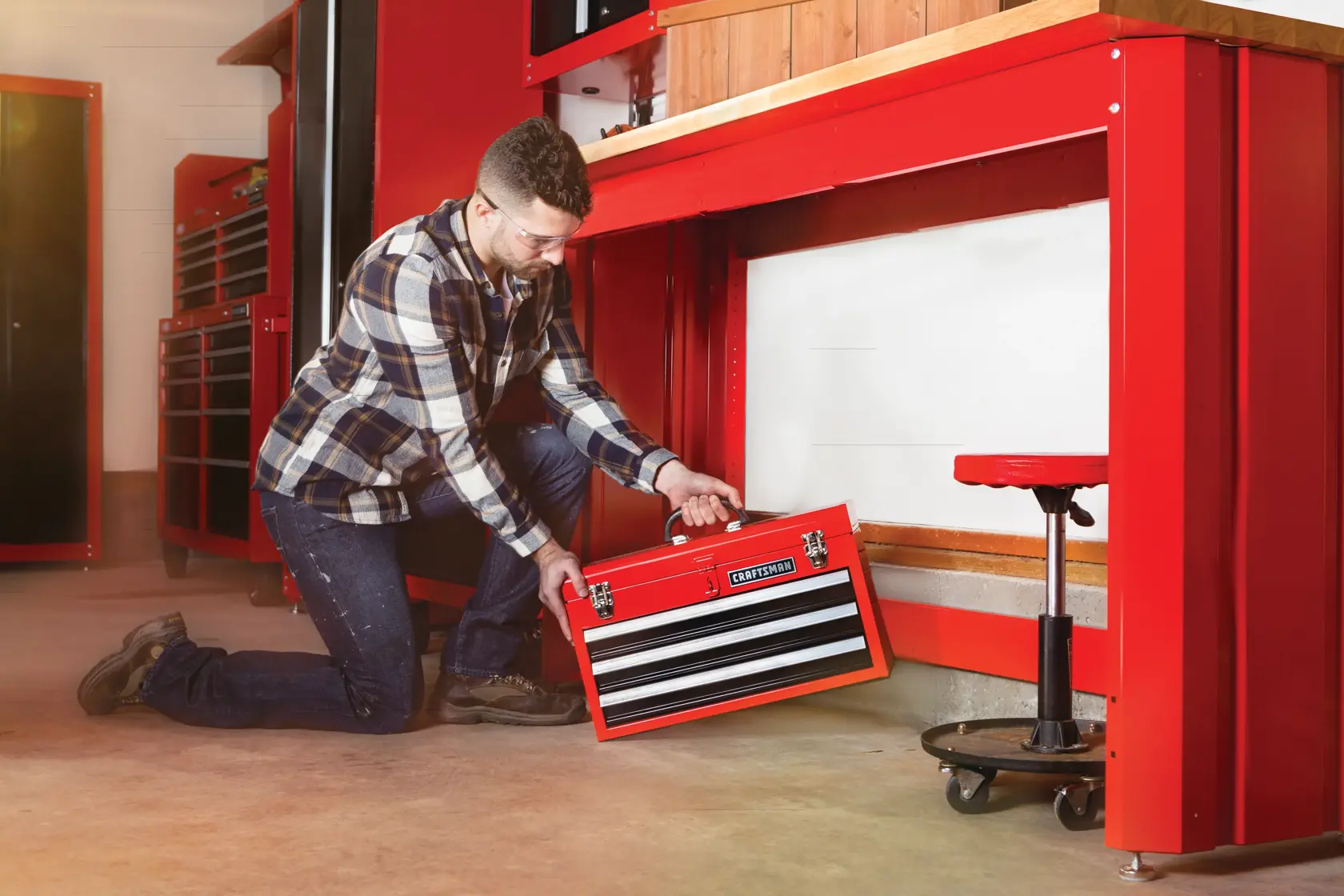 Portable 20 and 5 tenths inch Ball bearing 3 Drawer Red Steel Lockable Tool Box being stored by person under workstation.