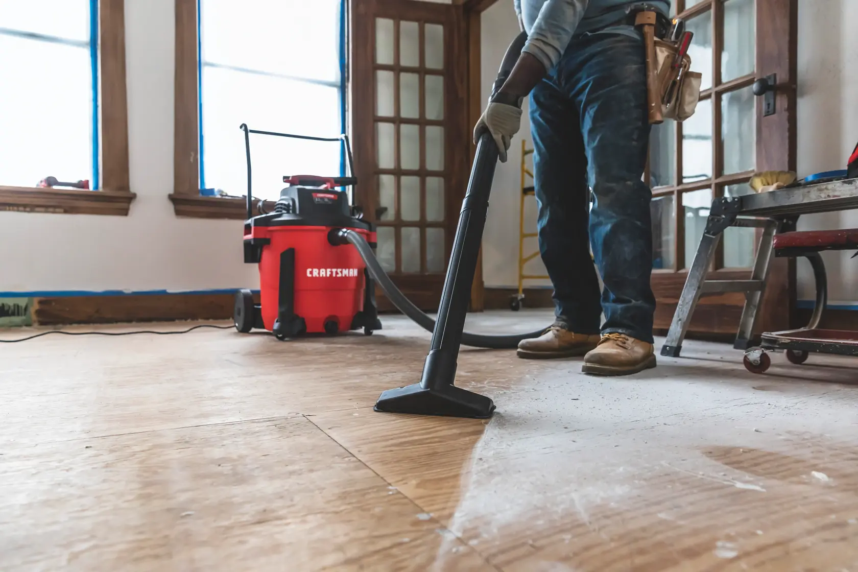 20 gallon 6.5 H P wet dry vacuum with cart being used by a person to clean wooden floor.