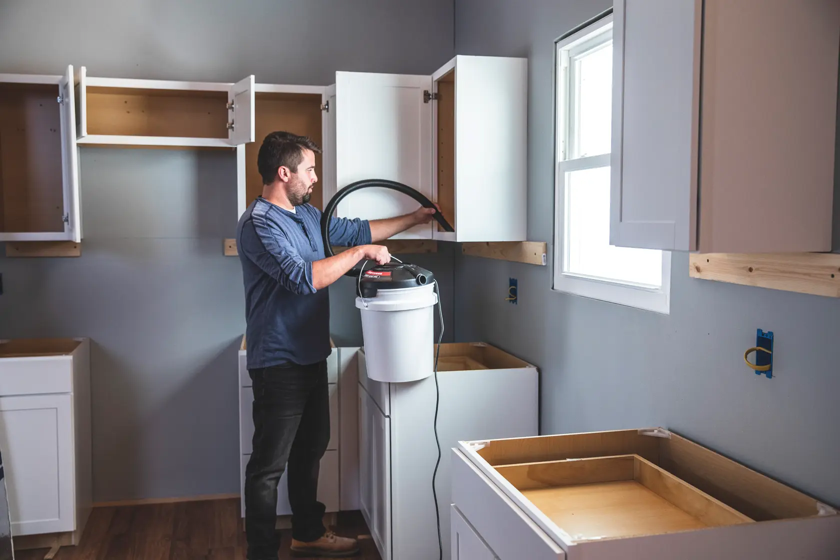 1.75 peak H P powerhead bucket head wet dry vacuum being used by a person to clean wooden cabinet.