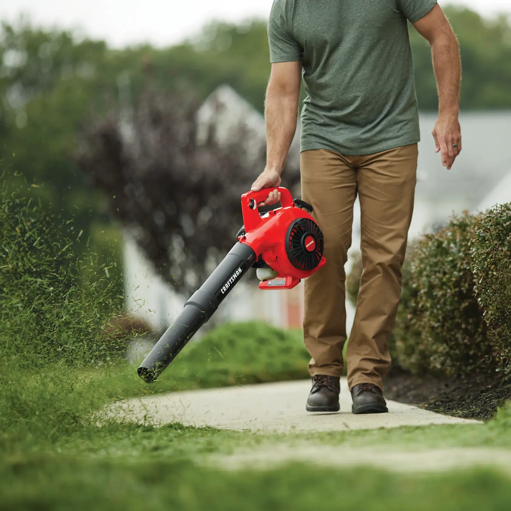 25 C C 2 cycle leaf blower being used by a person to remove leaves outdoors.
