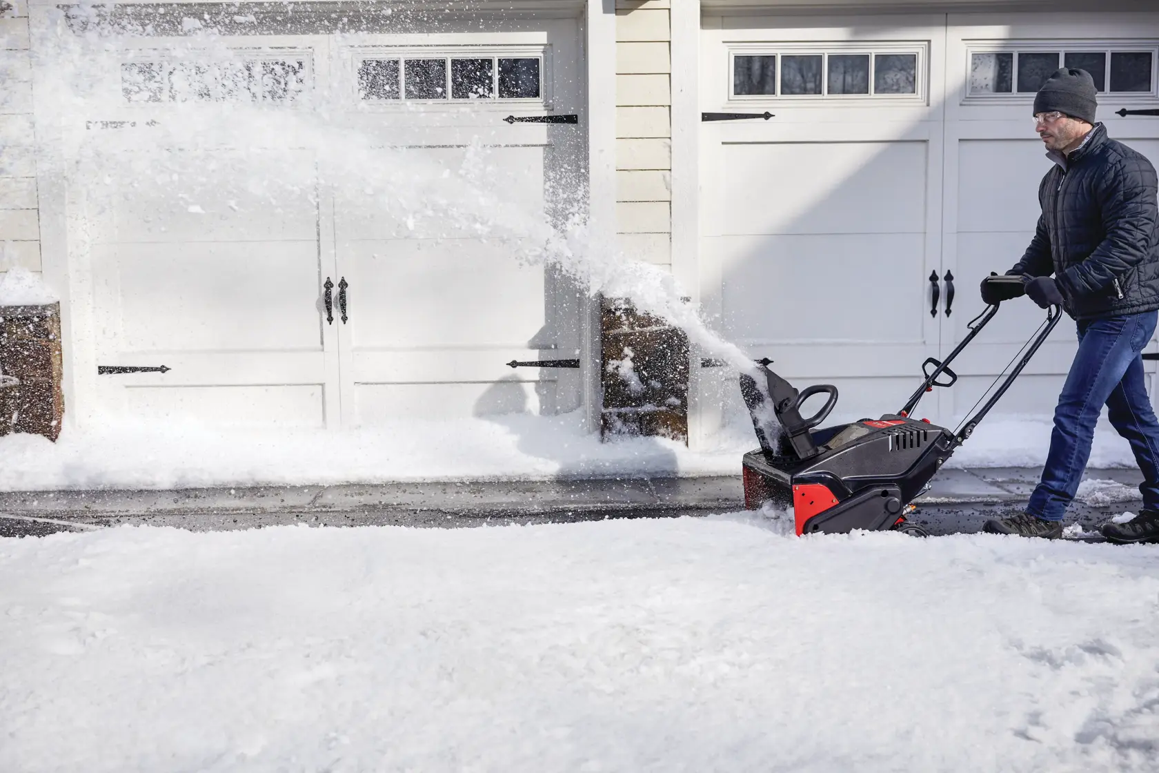 CRAFTSMAN Electric Start Single-Stage Snow Blower in side view blowing snow in driveway with black jacket 