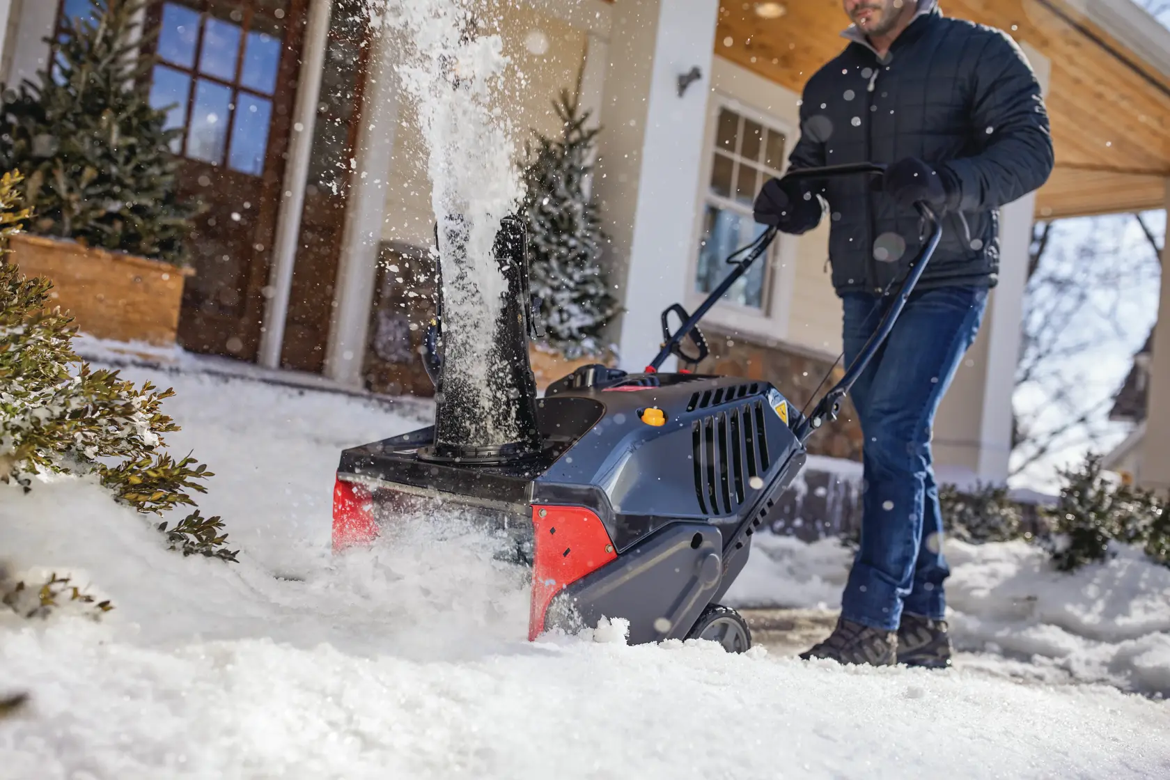 CRAFTSMAN Electric Start Single Stage Snow Blower in front view blowing the snow in front of the house in black coat 