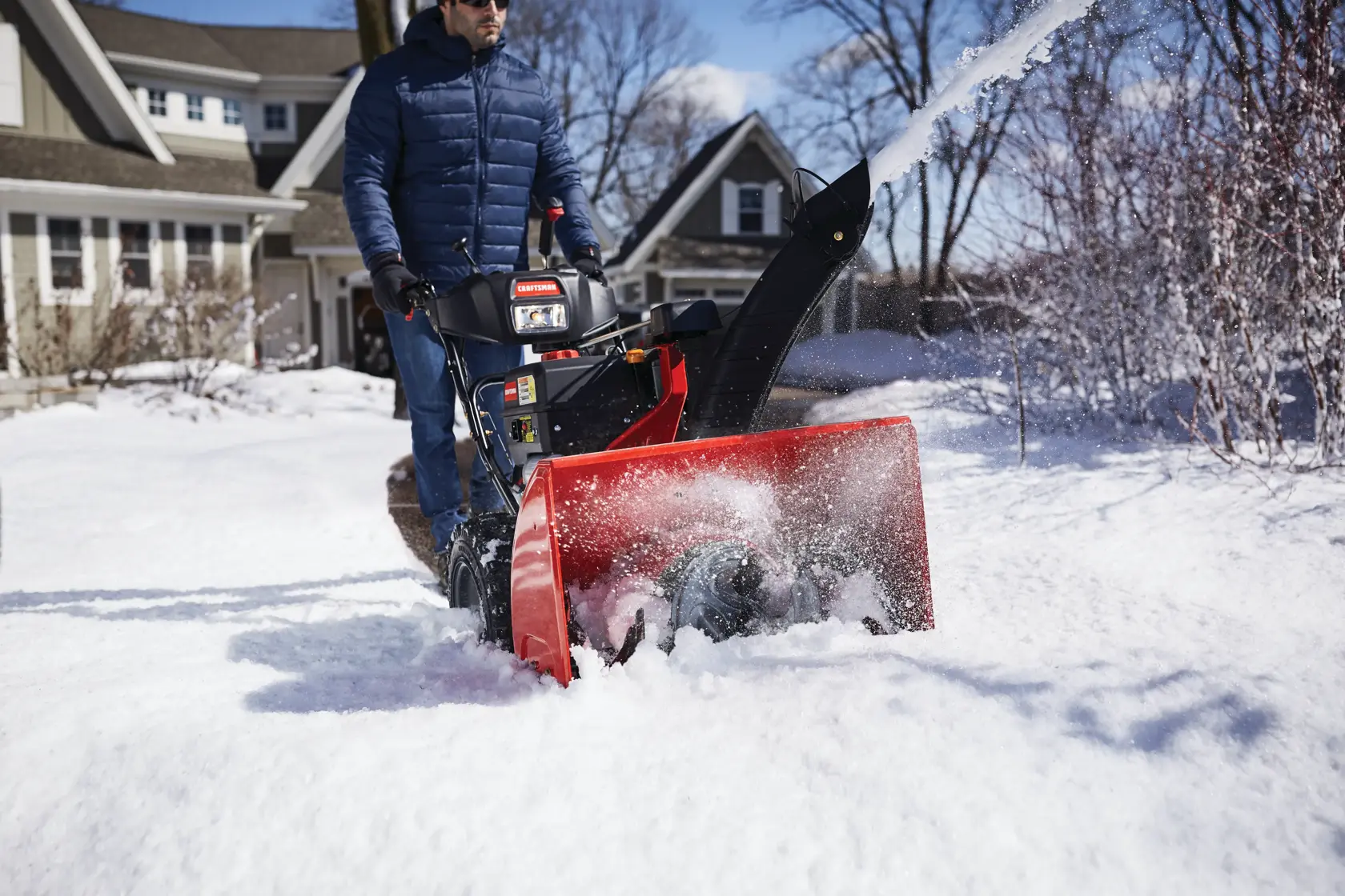 CRAFTSMAN Electric Start 3-Stage Snow Blower blowing the snow in a yard in front view in blue jacket