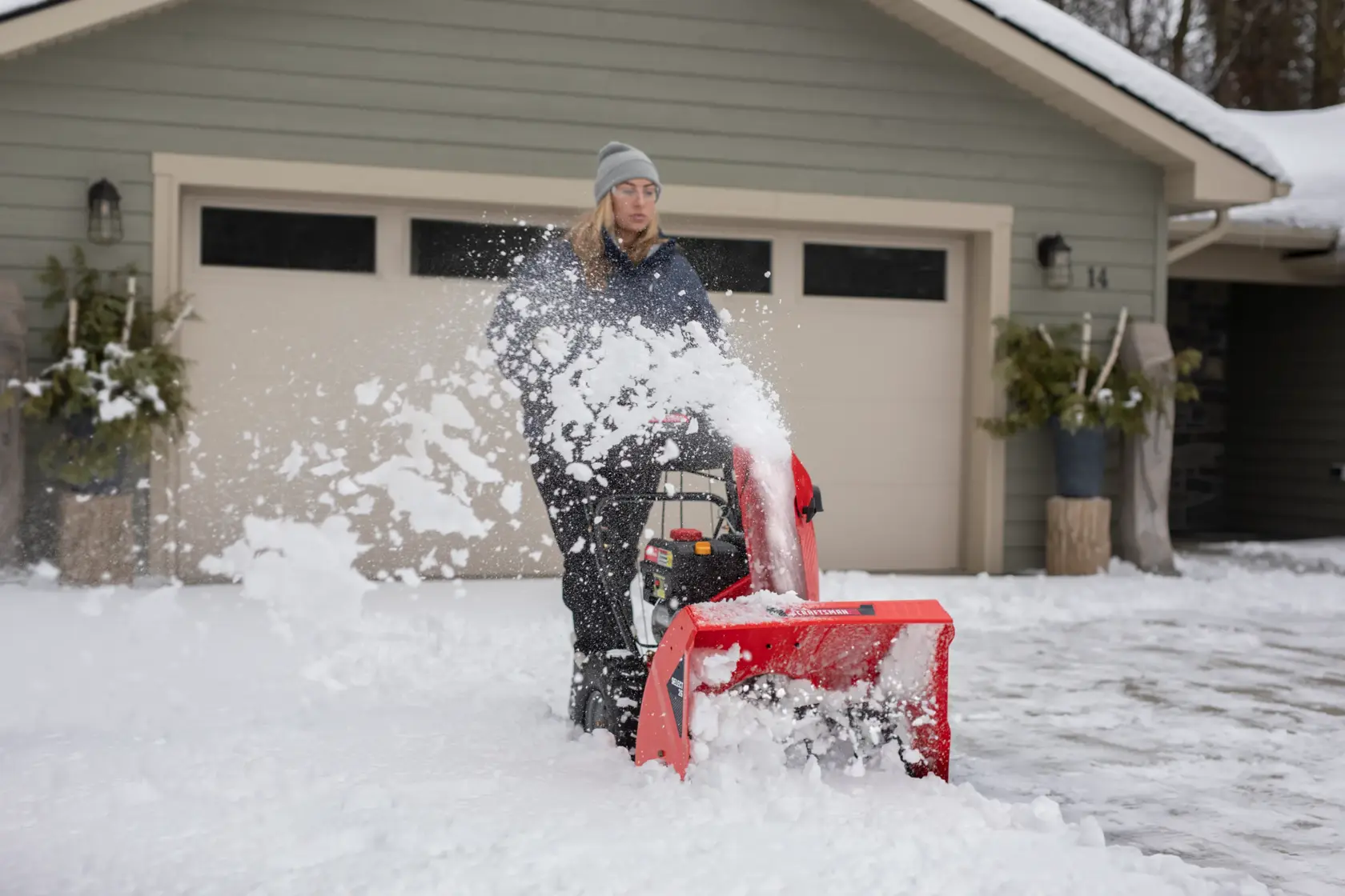 SELECT 26 inch 243 CC two stage gas snow blower with push button electric start being used by a person.