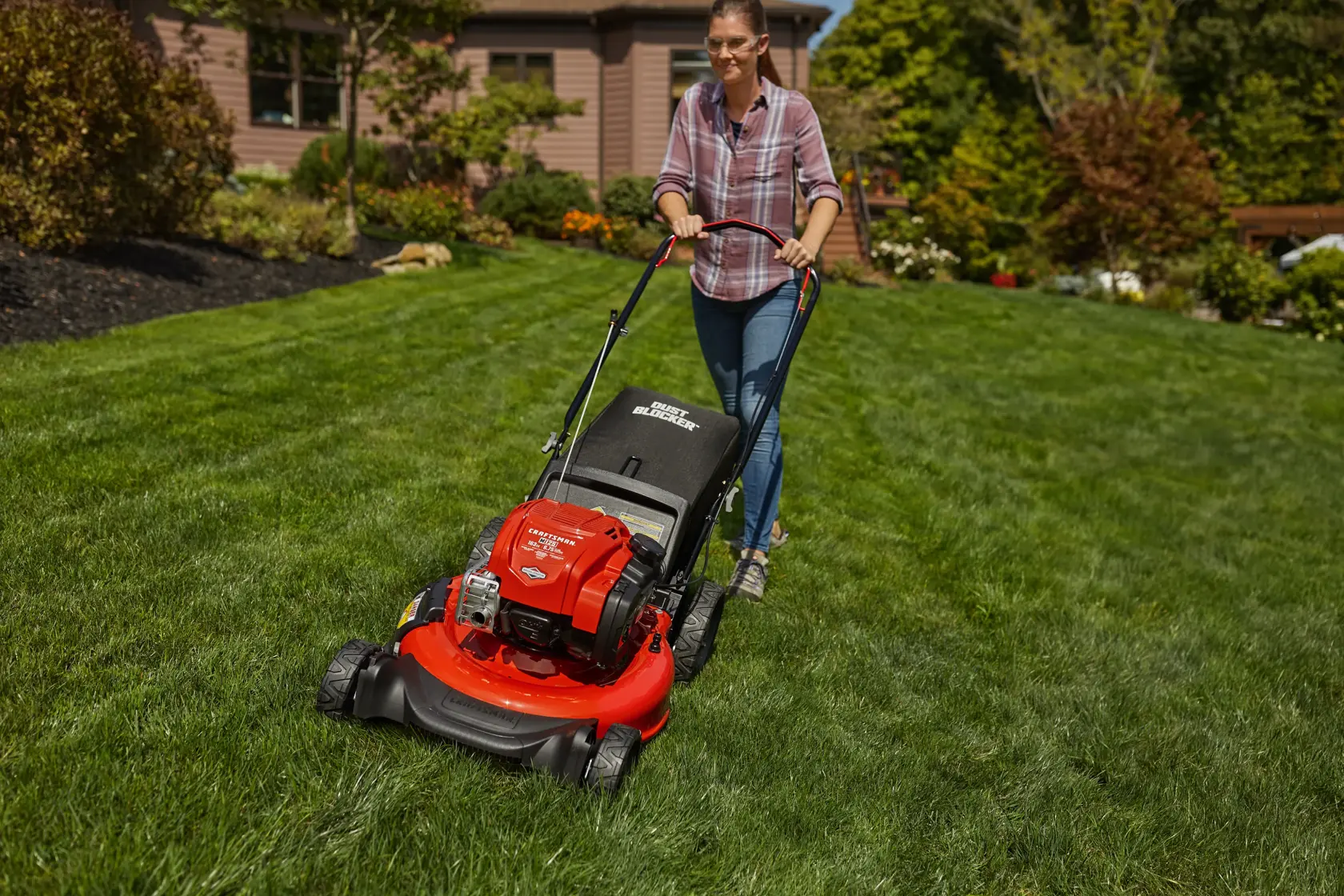 CRAFTSMAN M125 Push Mower mowing the grass in the backyard in front view in plaid shirt