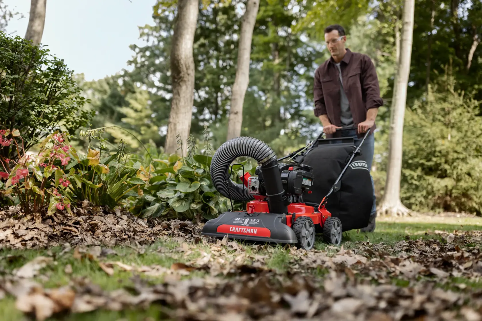 CRAFTSMAN 24-In. 163cc Chipper Shredder Vacuum attached to mower mowing up leaves in wooded area