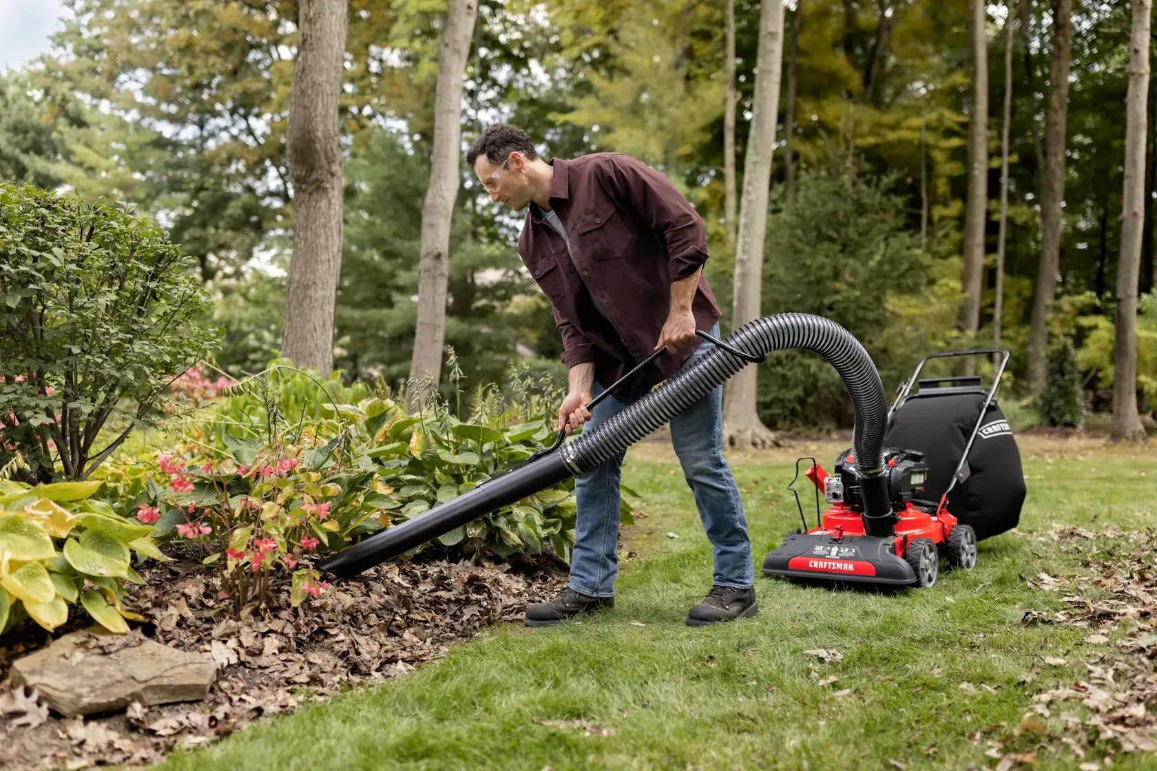 CRAFTSMAN 24-In. 163cc Chipper Shredder Vacuum attached to mower using hand vacuum removing leaves in flowerbed