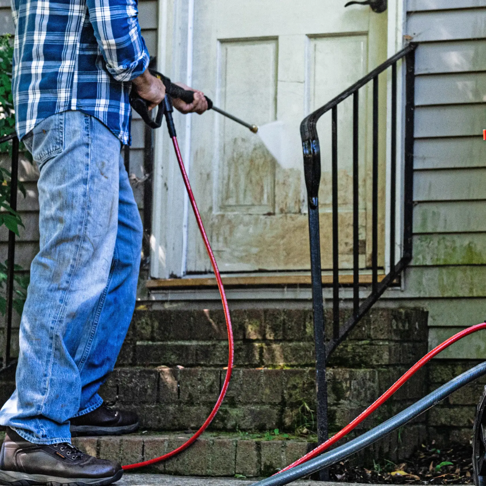 Photo of Craftsman pressure washer CMXGWFN061326 cleaning a dirty door and steps outdoors.