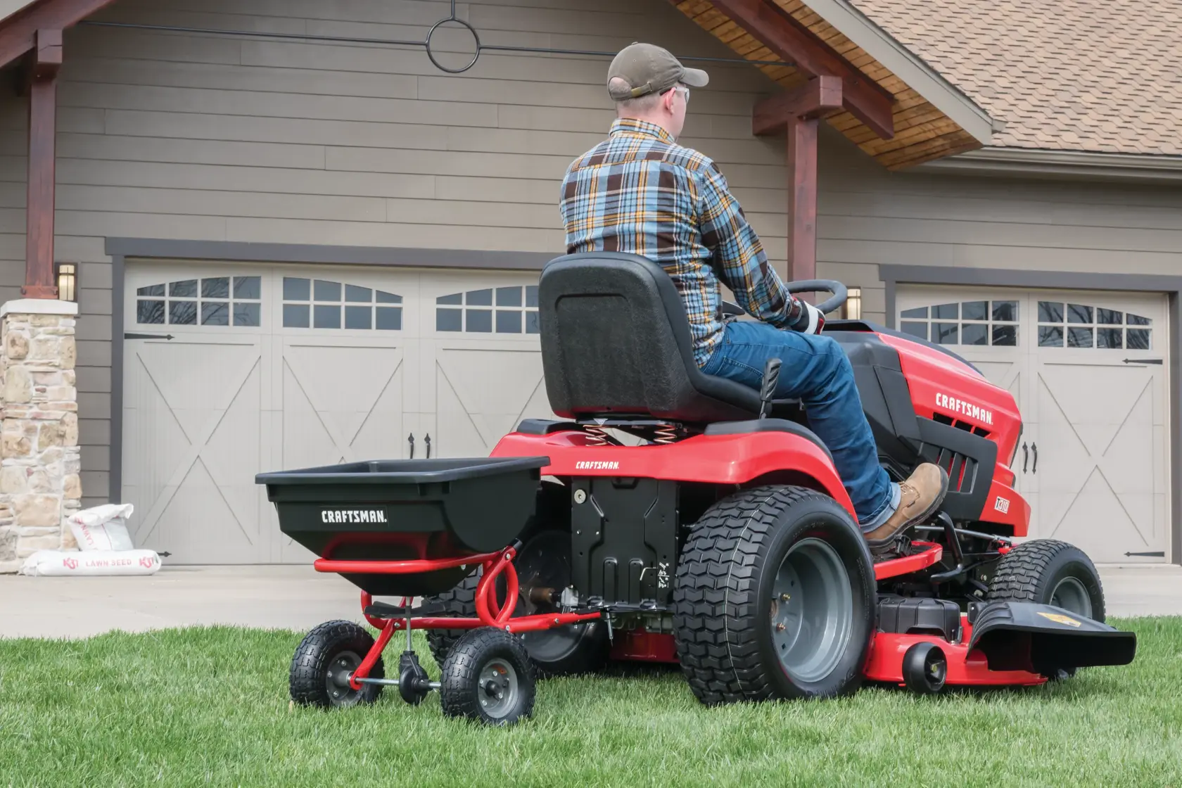 85 pounds tow broadcast spreader being used to spread seeds in lawn by person.