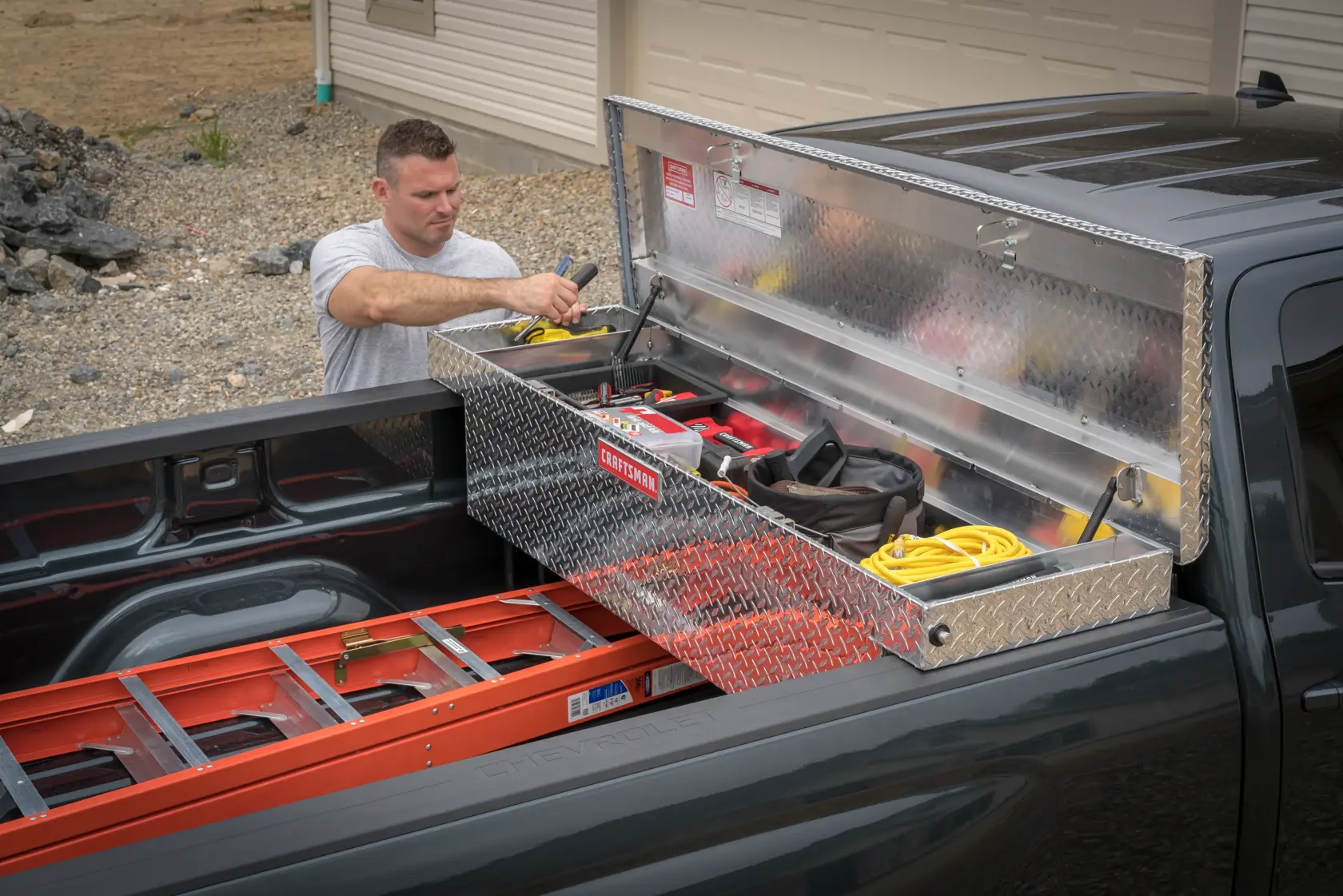 Photo of a Craftsman truck toolbox, SKU CMXTBAK1000901, installed in a black pickup truck with lumber in the bed.