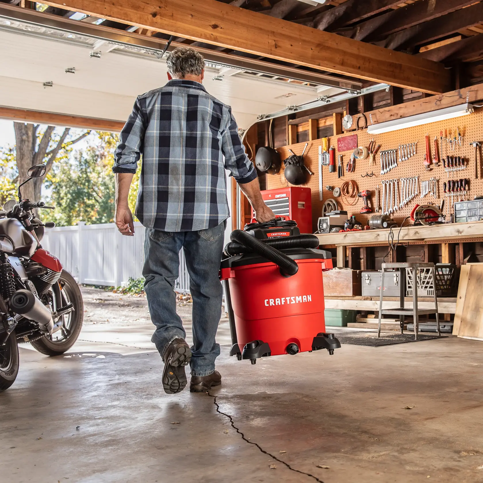 Man carrying the CRAFTSMAN Wet/Dry Vac in a garage by convenient handle 