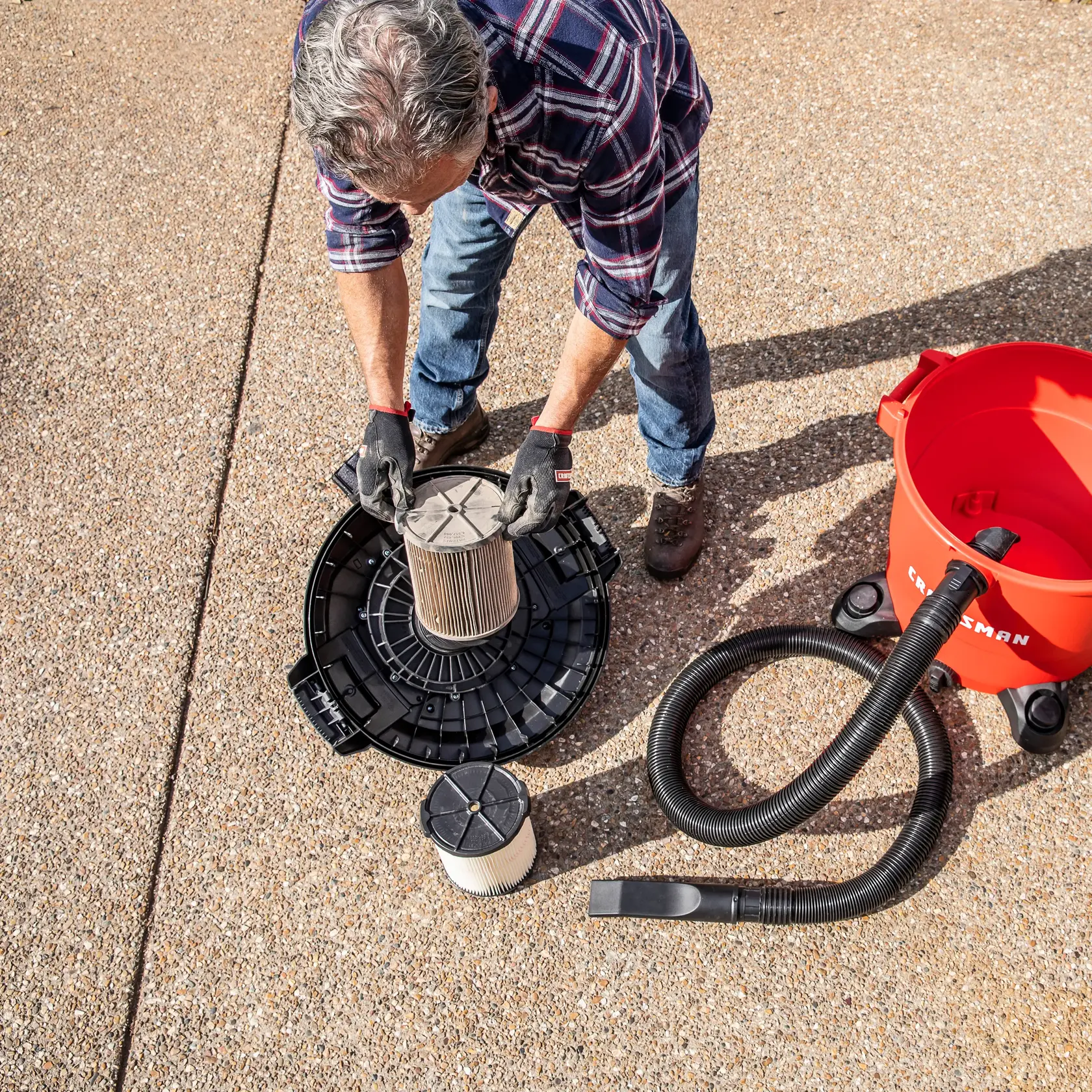 Man replacing dirty CRAFTSMAN General Dirt Replacement Filter on vac lid upside down on ground