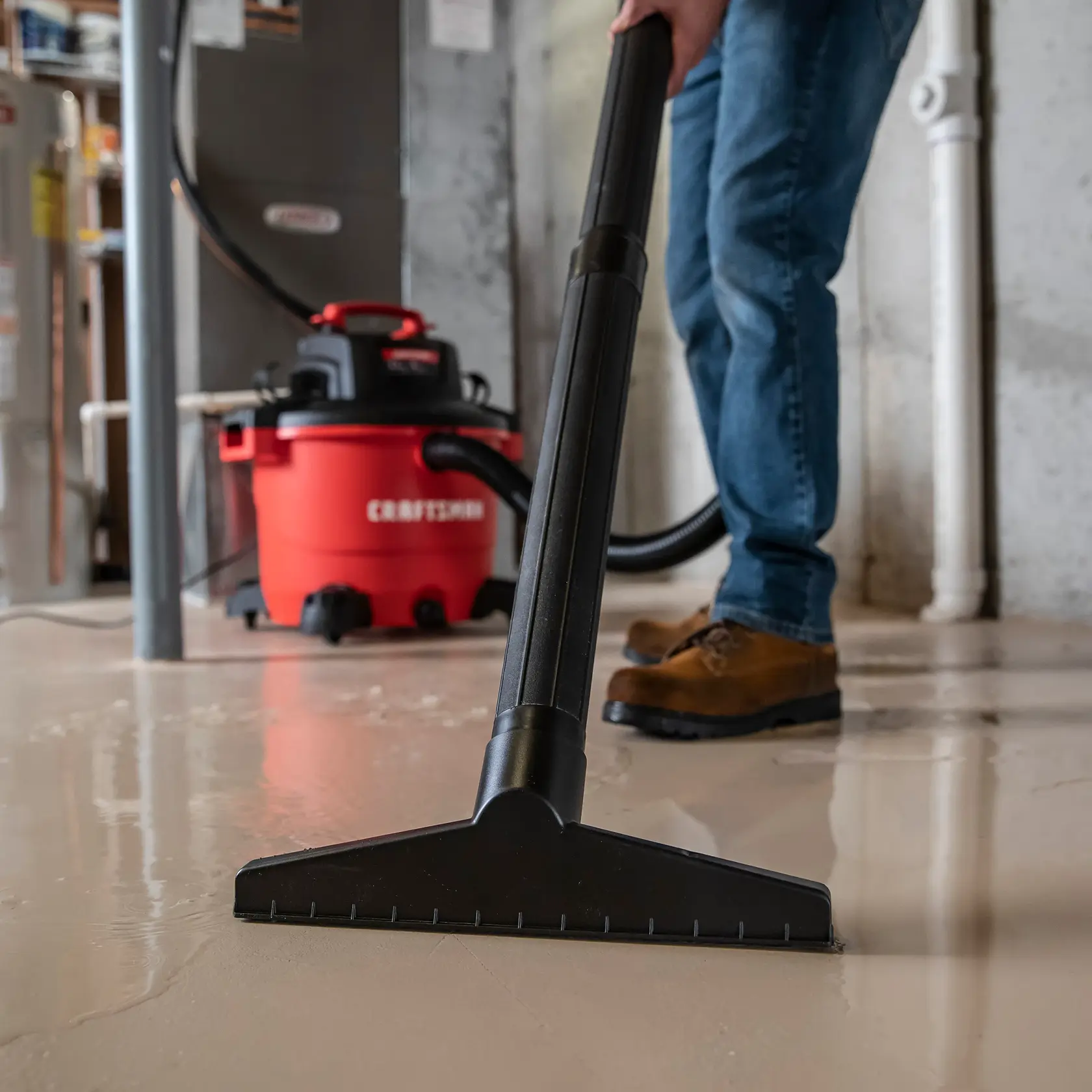 Photo of Craftsman wet/dry vacuum CMXZVBE38778 being used on a wet basement floor, close-up of large nozzle.