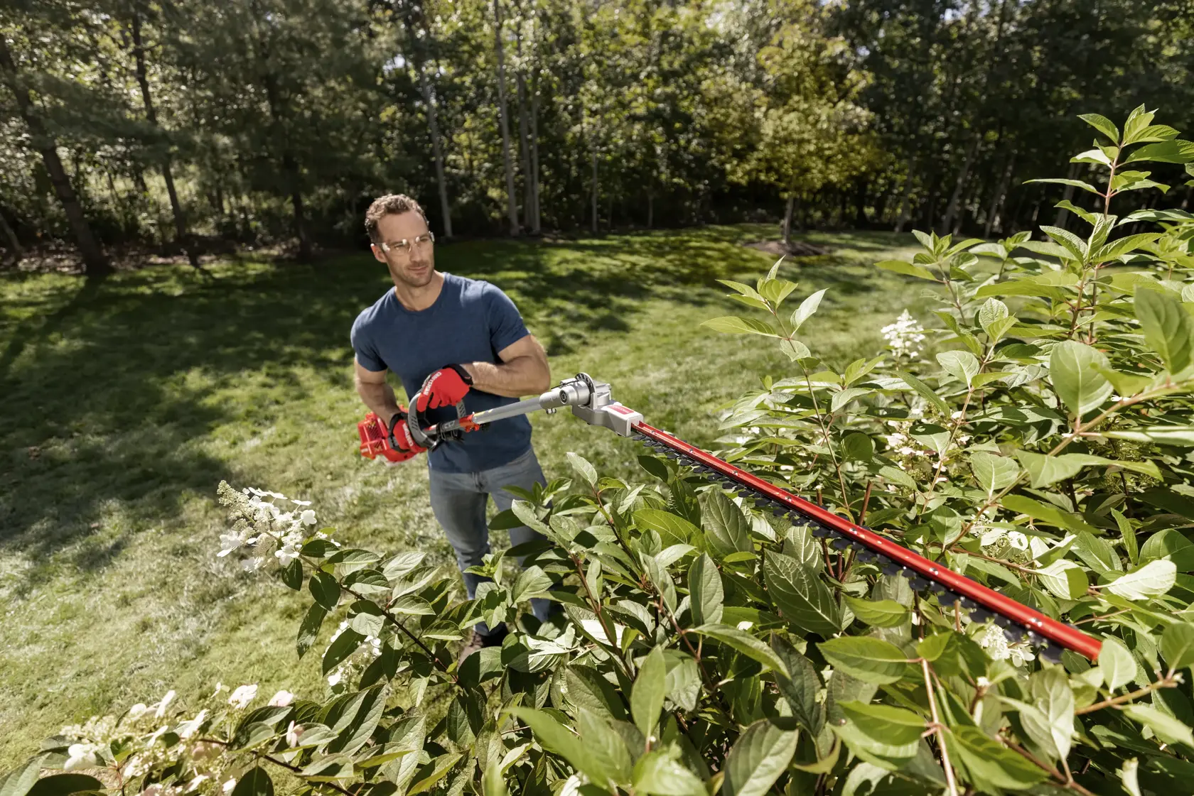 CRAFTSMAN hedge trimmer attachment from top view trimming bush in yard in blue shirt